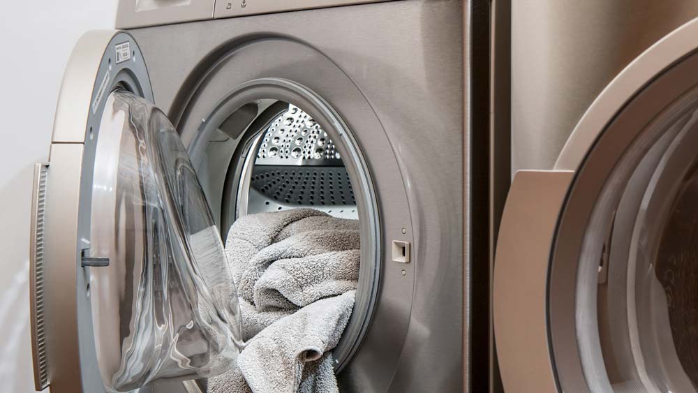 Washing machine, door open, with a grey towel