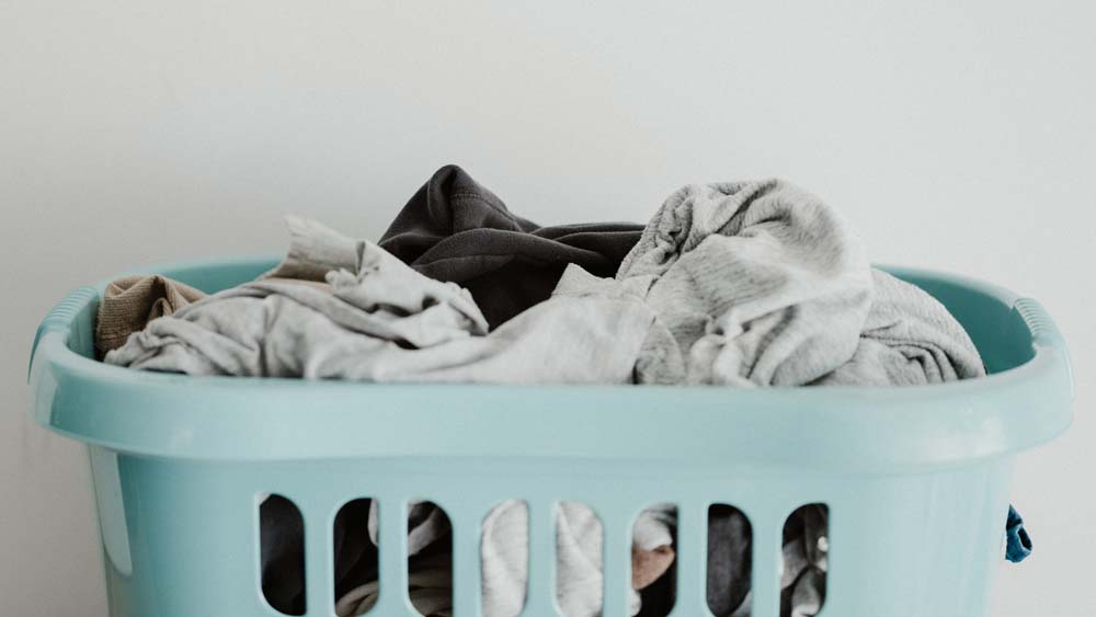 A blue laundry basket full of clothes