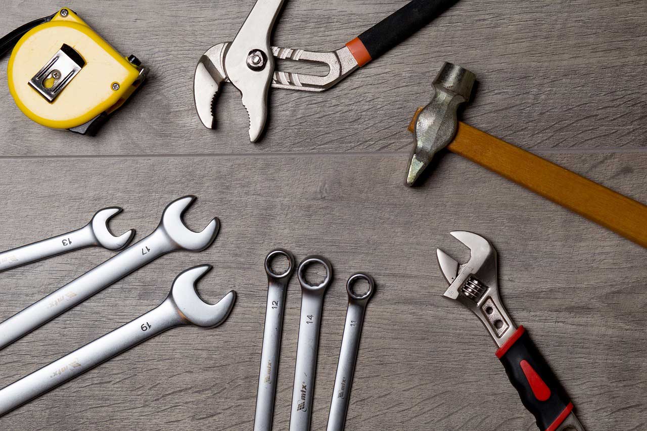 An assorment of hammers and wrenches on a grey tool bench